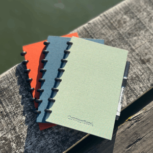 Carnets colorés sur banc en bois extérieur.