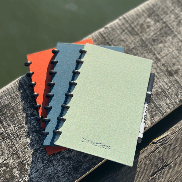 Carnets colorés sur banc en bois extérieur.
