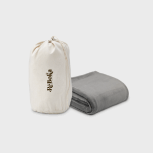 Sac et couverture pliée grise sur fond blanc.